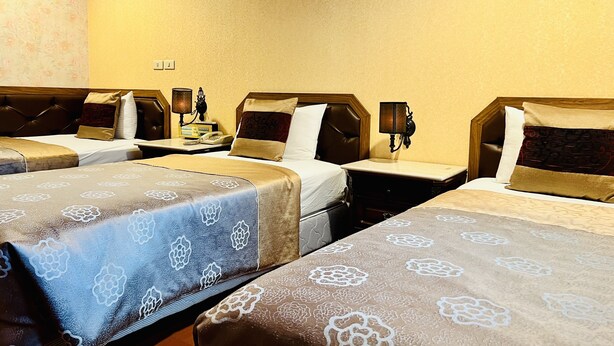 A hotel room with four single beds, each with a headboard and a bedside table with a lamp. - Shinyes Motel (Suao)