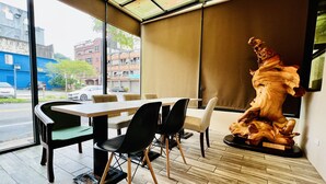 A modern dining area with a large table, chairs, and a unique wooden sculpture. - Shinyes Motel (Suao)