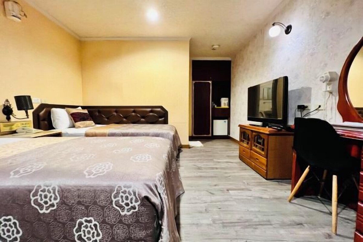 Une chambre d’hôtel avec deux lits, une télévision, un bureau et un miroir.