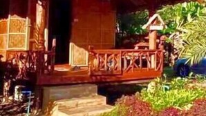 A wooden house with a porch, a staircase leading to the entrance, and a car parked nearby. - Wongwan Farm (Samoeng)