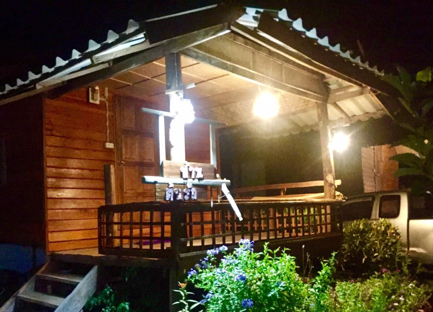 A wooden building with a porch, a small table, and a bench.