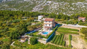 Una amplia casa con piscina, rodeada de exuberante vegetación y montañas.