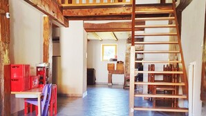 A spacious room with a wooden staircase, a dining area with a table and chairs, and a kitchen area with cabinets and a sink. - renovated farmhouse for groups and families in nature, dogs welcome, playground (La Chapelle-devant-Bruyères)