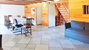 A spacious living area with a dining table and chairs, a blue sofa, and a staircase leading to another level. - renovated farmhouse for groups and families in nature, dogs welcome, playground (La Chapelle-devant-Bruyères)