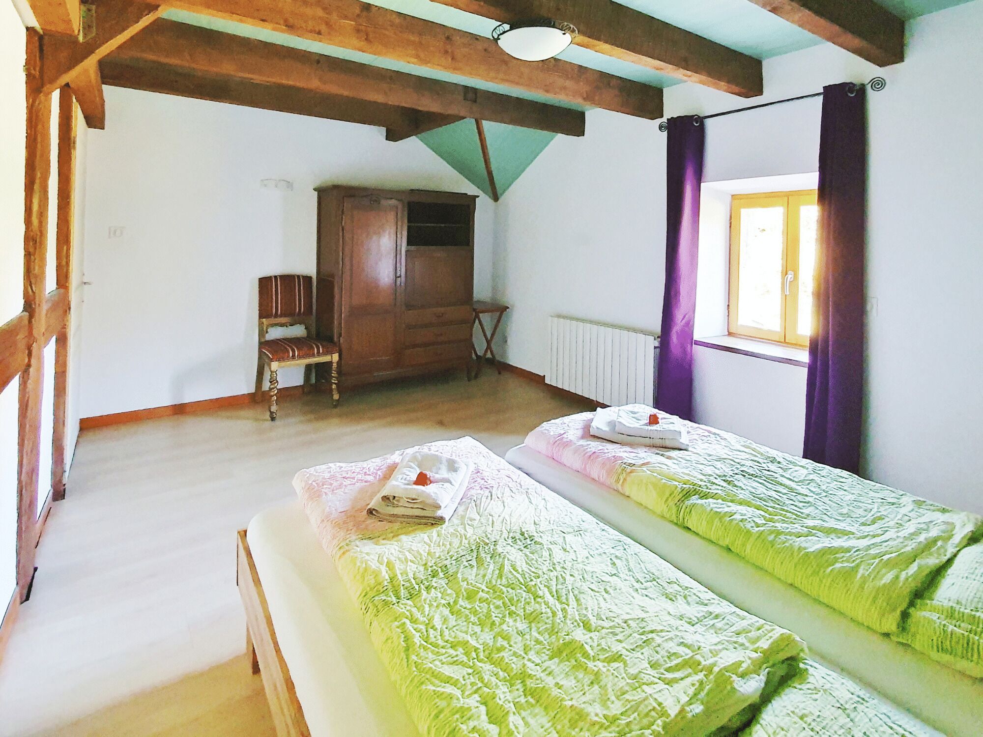 Een kamer met twee eenpersoonsbedden, houten meubels, een radiator en een raam met gordijnen.