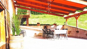 An outdoor patio with a wooden pergola, a dining table with chairs, and a large planter with tall plants. - renovated farmhouse for groups and families in nature, dogs welcome, playground (La Chapelle-devant-Bruyères)