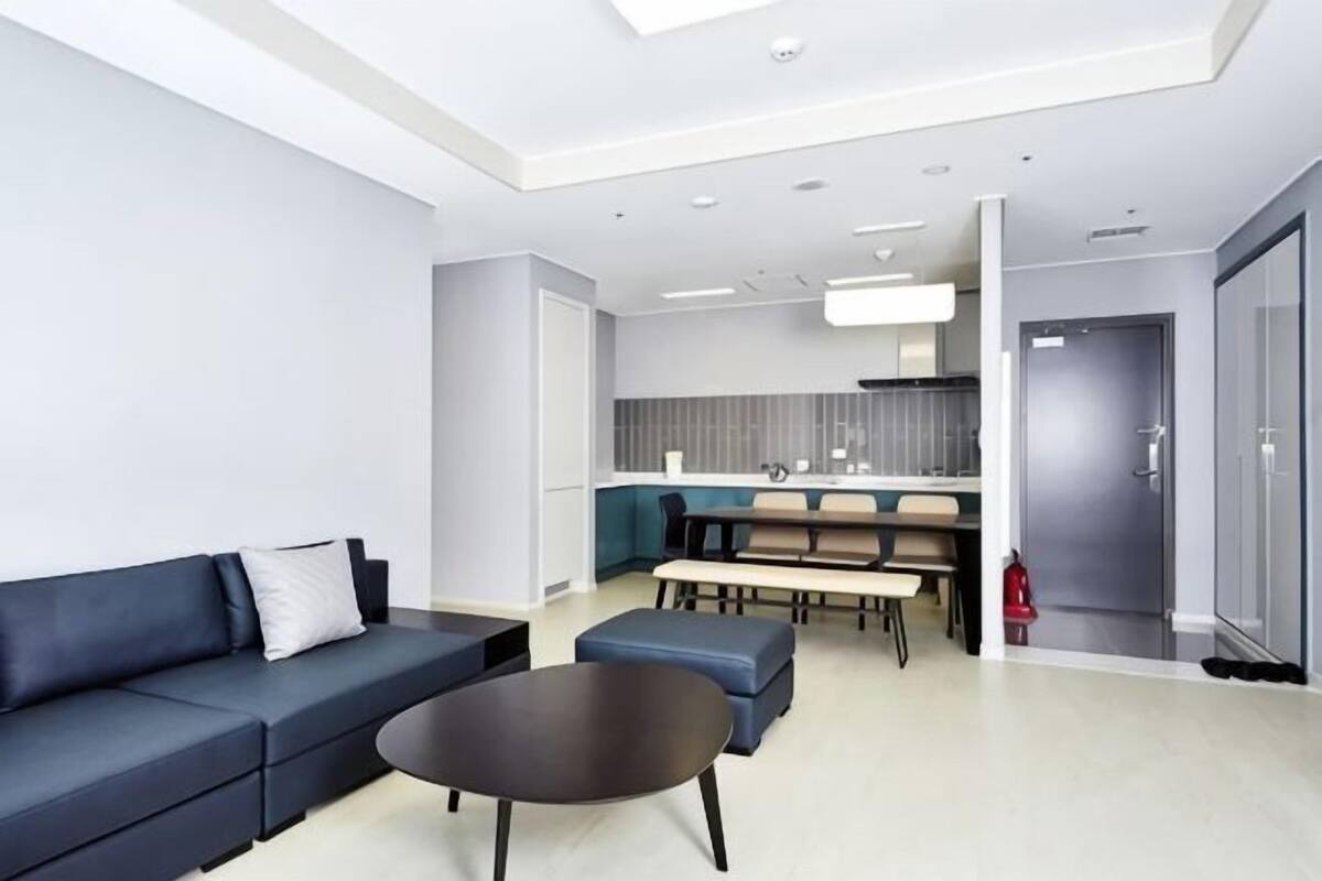 A modern living room with a sofa, coffee table, and a dining area with chairs and a table.