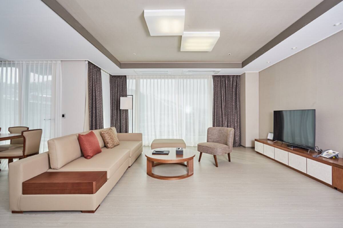 A modern living room with a sofa, armchair, coffee table, and a television on a stand.