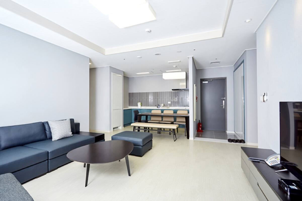 A modern living room with a sofa, coffee table, and a dining area with a bench.