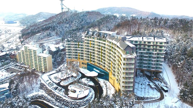 A multi-story hotel with a curved facade, a central courtyard, and a parking area. - I Want Resort (Pyeongchang)