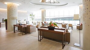 A modern hotel lobby with a central reception desk, comfortable seating areas, and large windows offering views of the city. - I Want Resort (Pyeongchang)