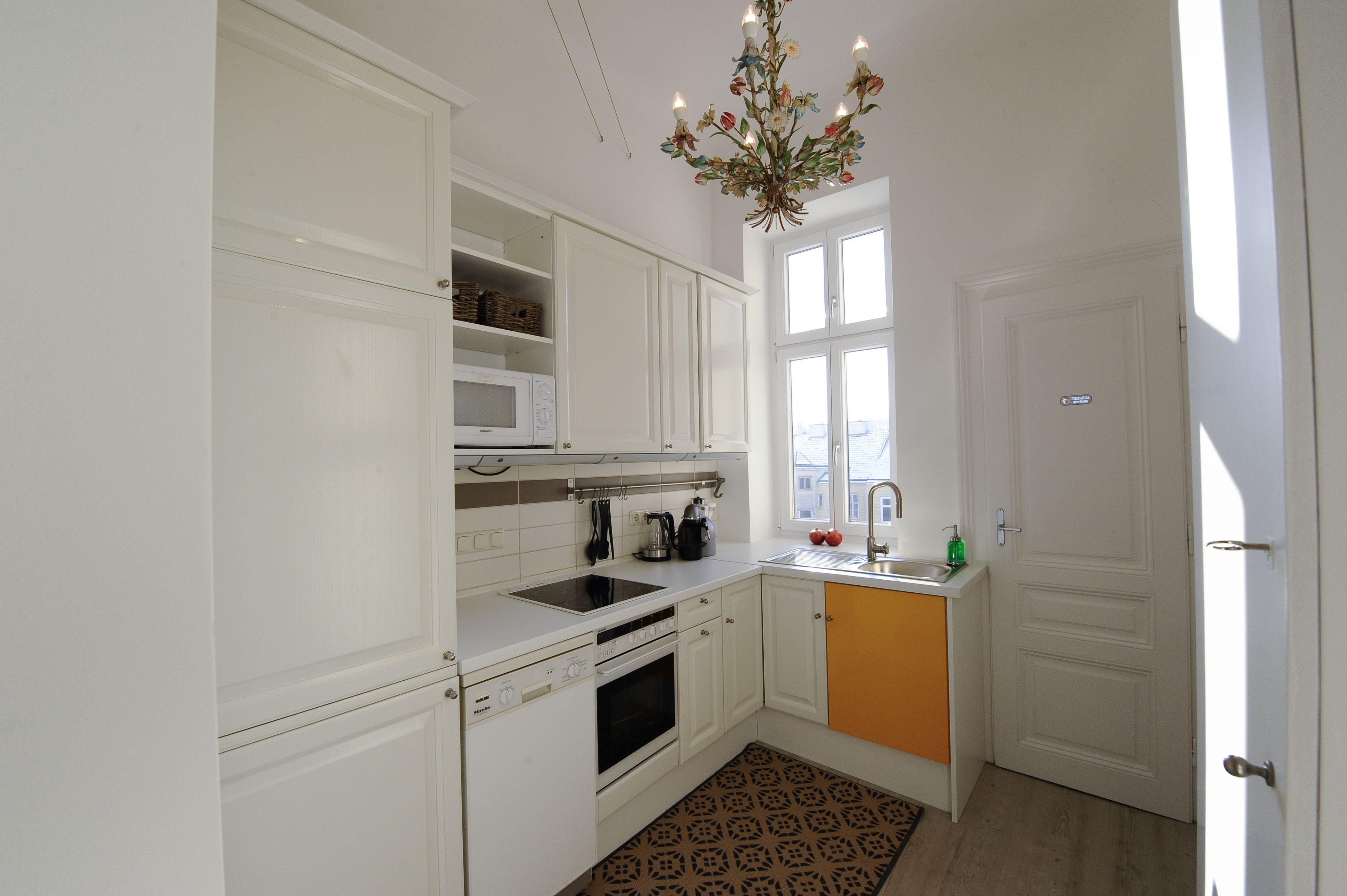 Una cocina moderna con armarios blancos, horno empotrado, microondas y fregadero.
