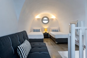 A compact, modern bedroom with two beds, a sofa, and a circular skylight. - White Harmony Suites (Santorini)