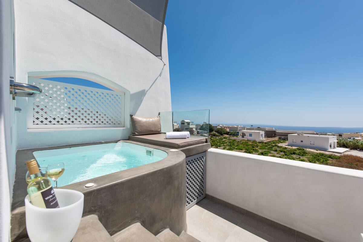 Un balcone con vasca idromassaggio, un parapetto in vetro e vista sul mare.