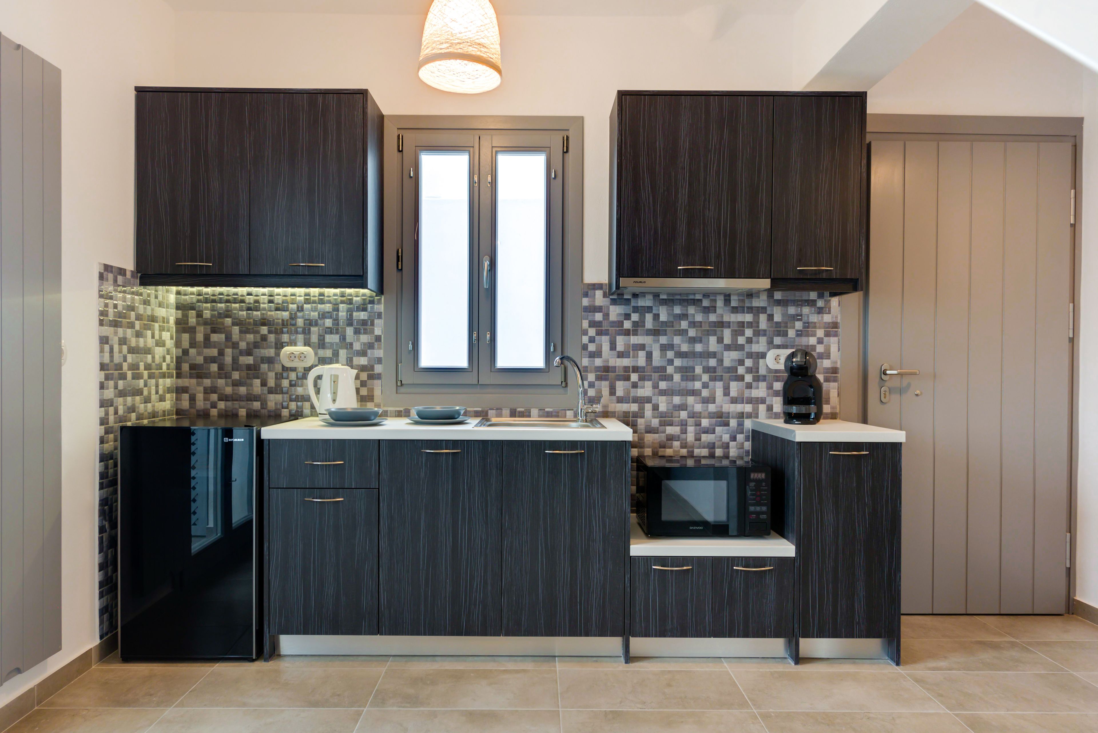 Una cocina moderna con alacenas de madera oscura, microondas integrado y salpicadero de azulejos.