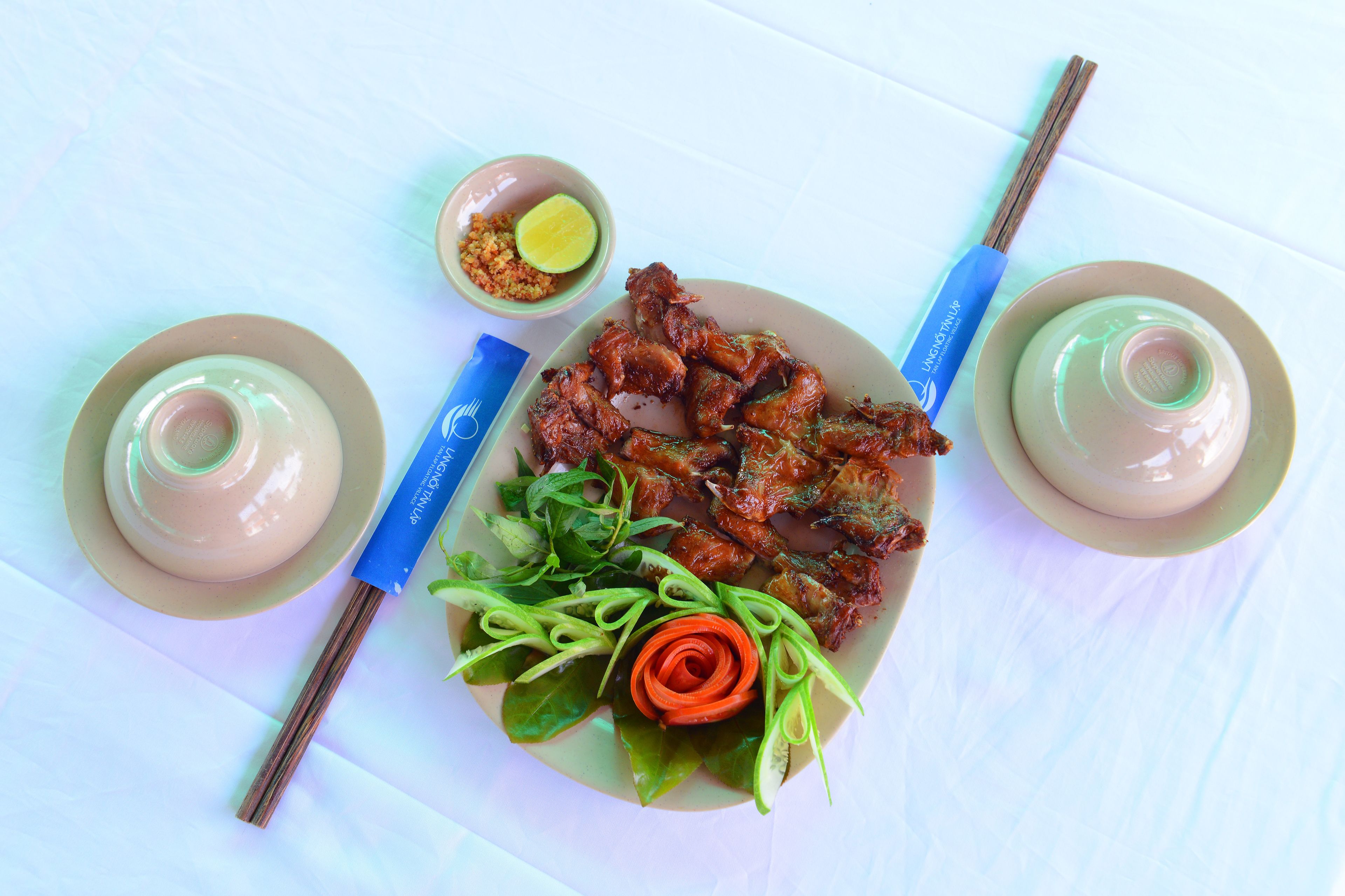 A plate of food with chopsticks and a small bowl of sauce.