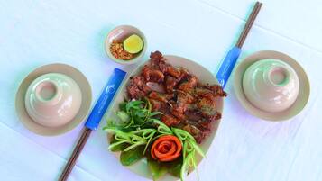 A plate of food with chopsticks and a small bowl of sauce.