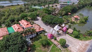 Vista aérea de um resort com vários edifícios, um rio e um calçadão pavimentado.