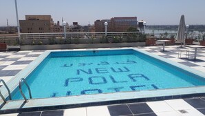 Una piscina en la azotea con suelo a cuadros y vistas de la ciudad de fondo.