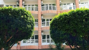 Un hotel de varios pisos con balcones, un cartel que dice 'Hotel XYZ' y un coche rojo estacionado al frente.