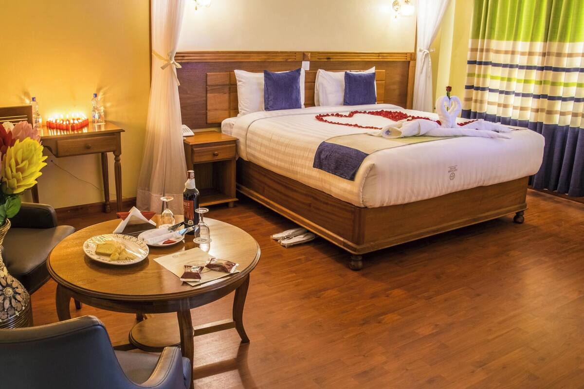 Una habitación de hotel con cama, mesita de noche y una mesa redonda con un plato de comida y una botella.