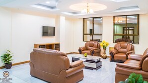 A spacious living room with leather sofas, a coffee table, and a TV. - Eastmark Hotel (Nakuru)
