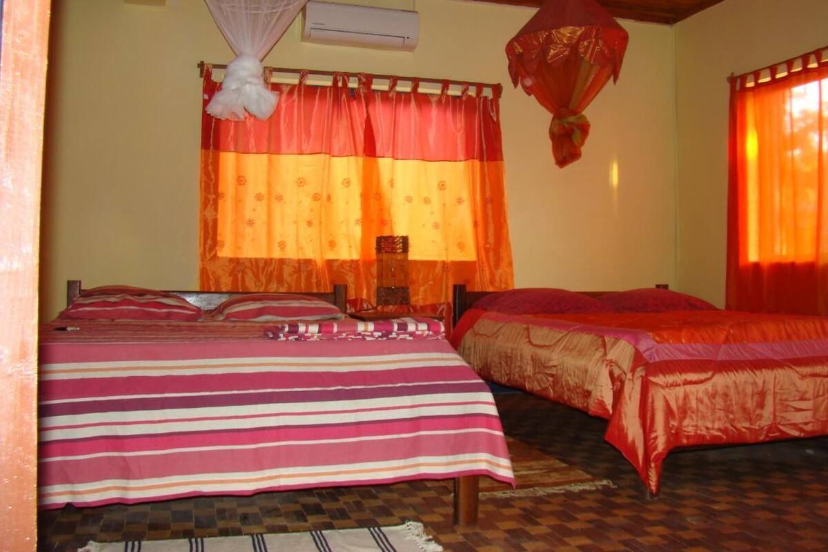 Una habitación con dos camas, un mosquitero y una ventana con cortinas.