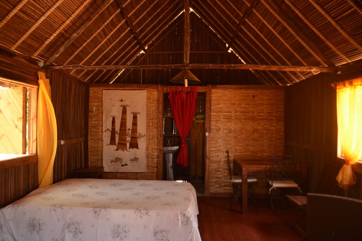 Una habitación rústica con una cama, una mesita y una silla.