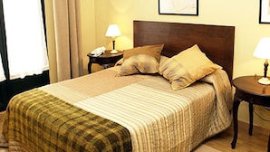 Ein Hotelzimmer mit einem großen Bett, zwei Nachttischen, einer Lampe auf jedem Tisch und einem Telefon auf einem der Tische.