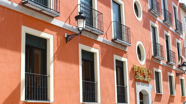 Eine Hotelfassade mit mehreren Balkonen, großen Fenstern mit schwarzen Geländern und einer auffälligen Hotelschild.