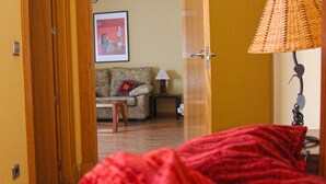 Ein Zimmer mit Holztür, einem gemusterten Sofa, einem kleinen Tisch und einer Lampe.