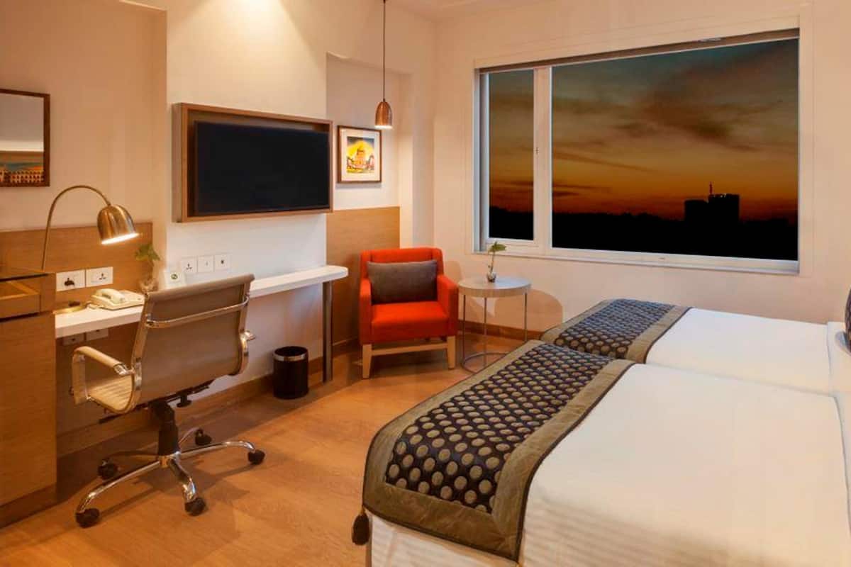 Ein Hotelzimmer mit Schreibtisch, Stuhl und einem Bett mit gemustertem Überwurf.