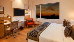 A hotel room with a desk, chair, and a bed with a patterned bedspread. - Lemon Tree Hotel Lucknow (Lucknow)