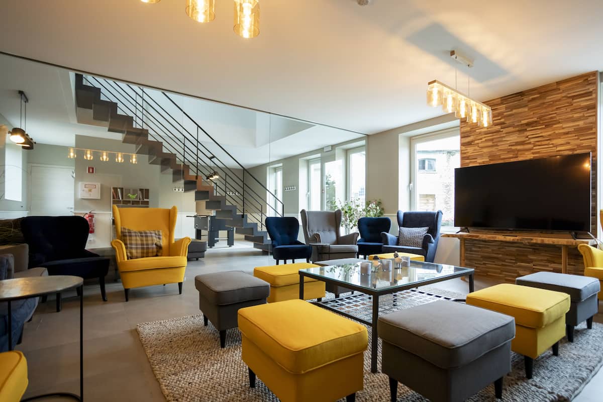 A modern living room with a glass staircase, comfortable seating, a flat-screen TV, and a wooden accent wall.