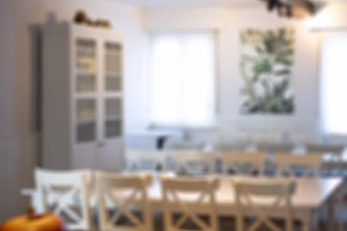 A modern kitchen with white cabinetry, a dining area with wooden chairs, and a large window providing natural light.