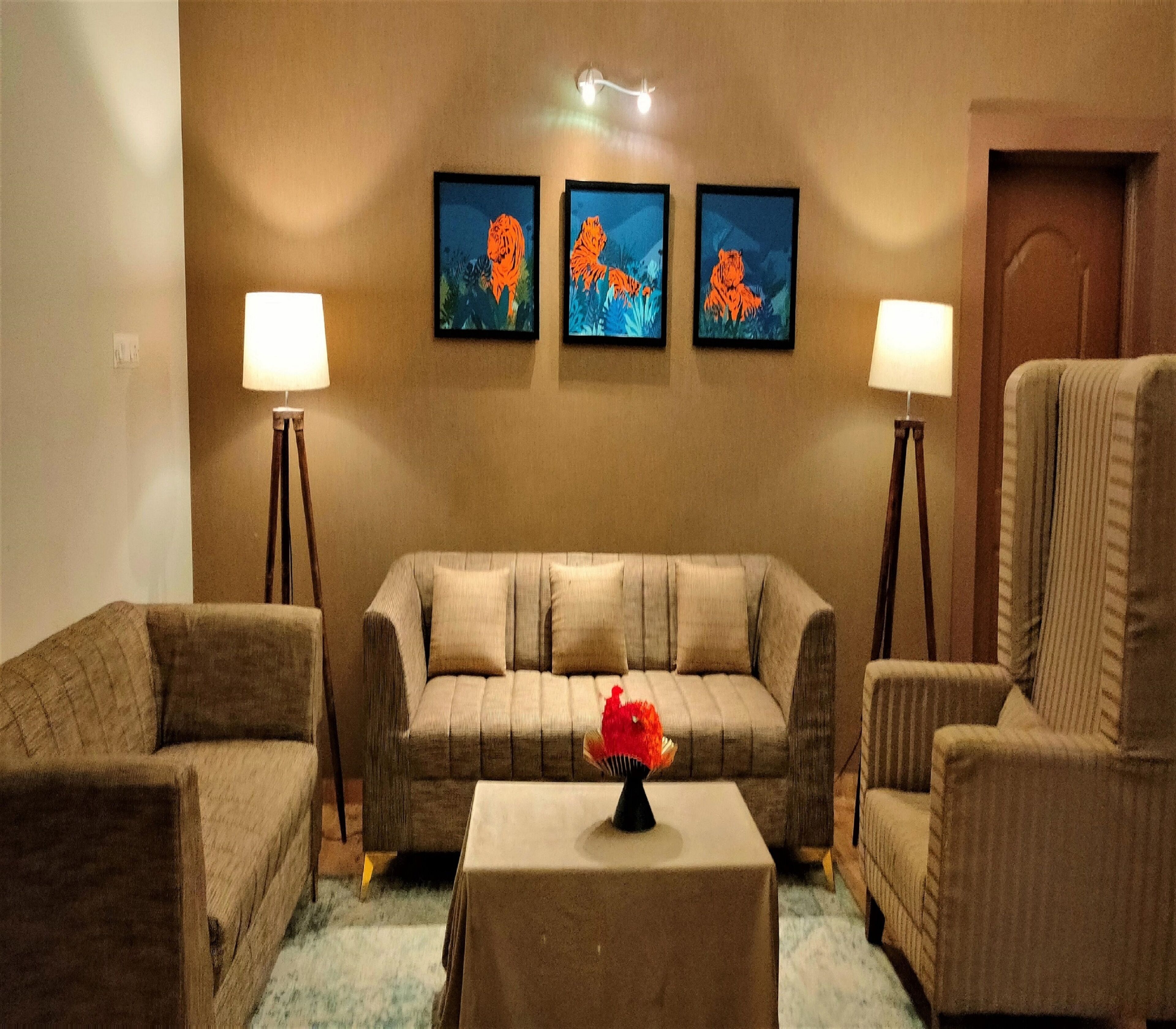 A living room with a sofa, two armchairs, a coffee table, and three framed pictures on the wall.