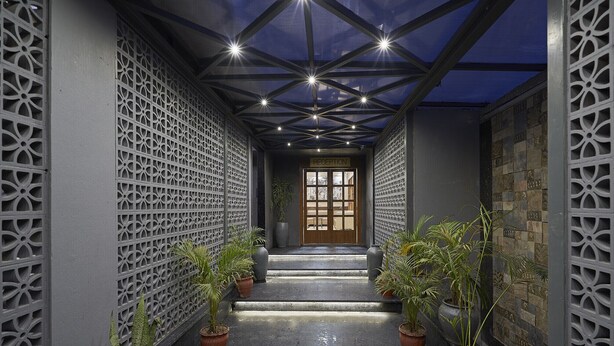 A hallway with a reception at the end, flanked by decorative walls and potted plants. - Olive Resorts & Villas (Kurai)