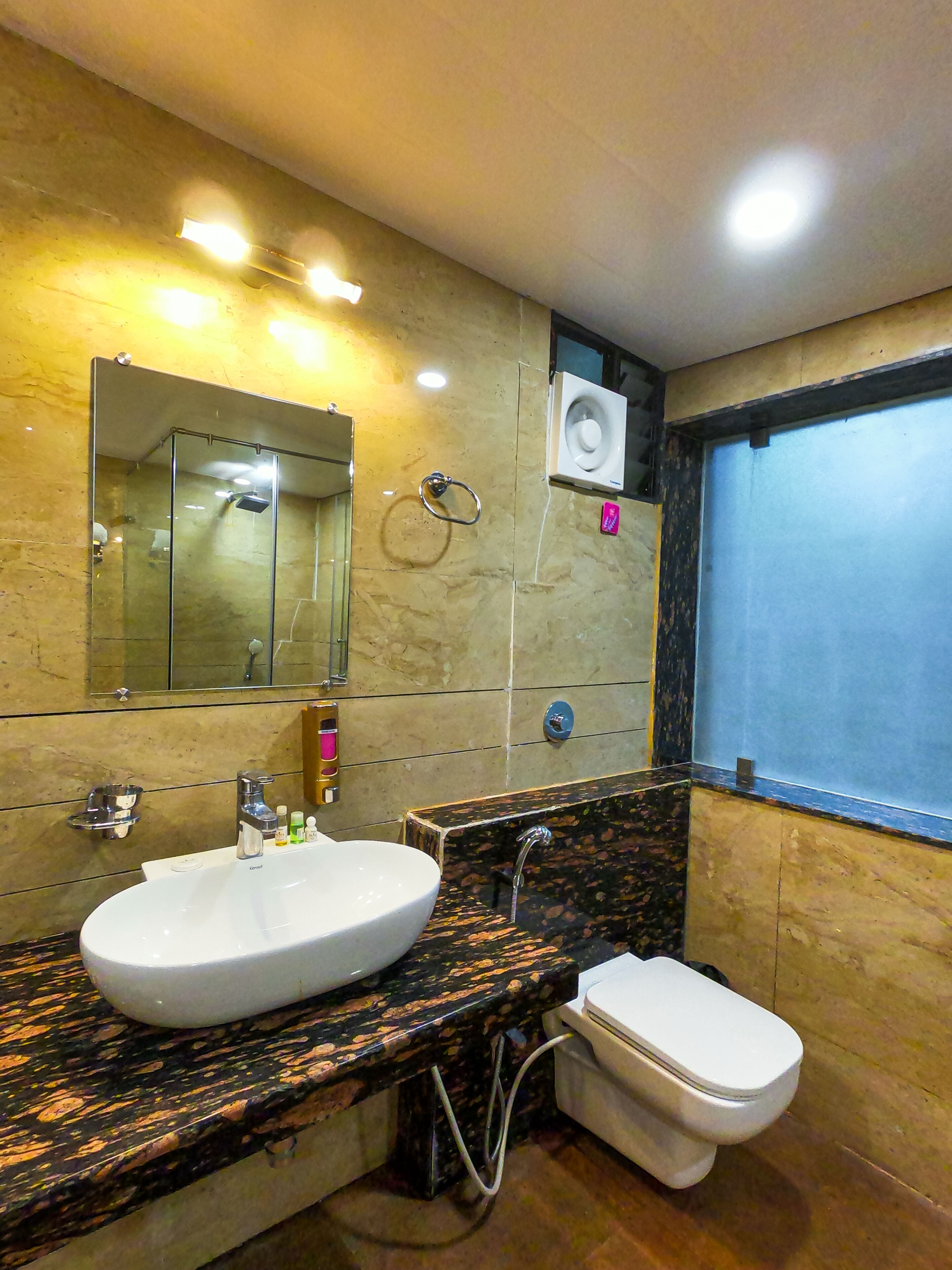 A bathroom with a white sink, a mirror, a toilet, and a window.