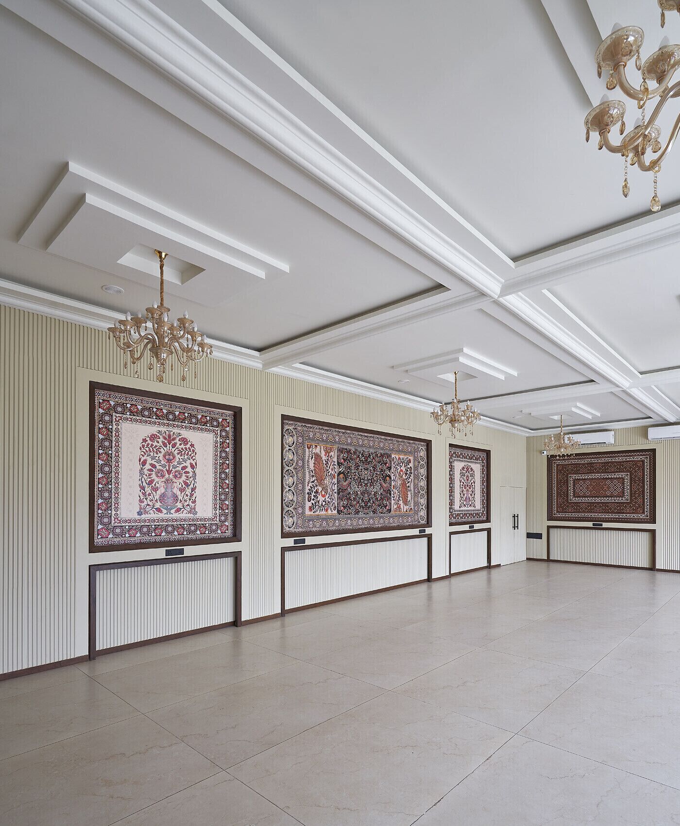 A spacious room with high ceilings, decorative moldings, and ornate chandeliers.