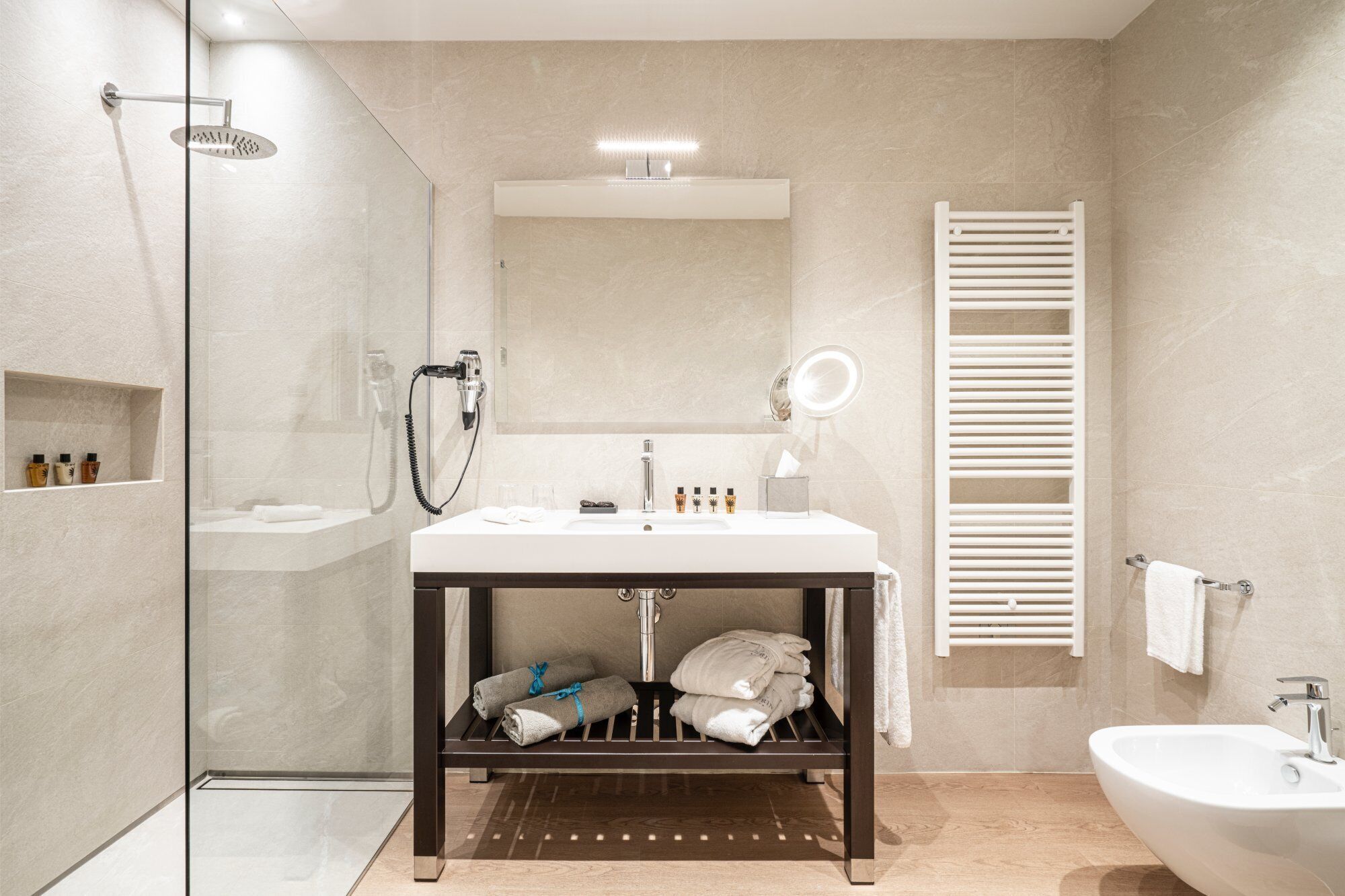 Un baño moderno con cabina de ducha de vidrio, tocador con espejo y barra para toallas.