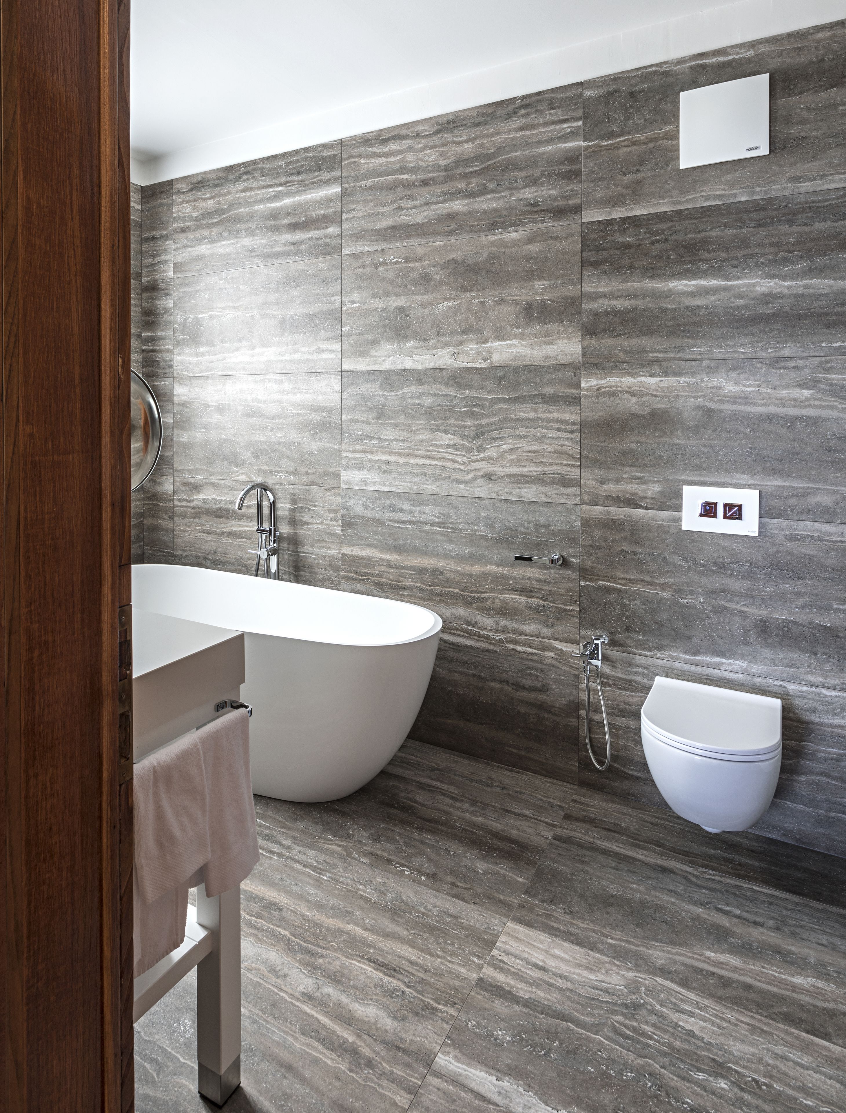 A modern bathroom with a freestanding bathtub, a wall-mounted sink, and a toilet.
