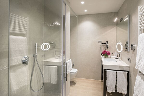A modern bathroom with a glass-enclosed shower, a white sink with a mirror, and a toilet.