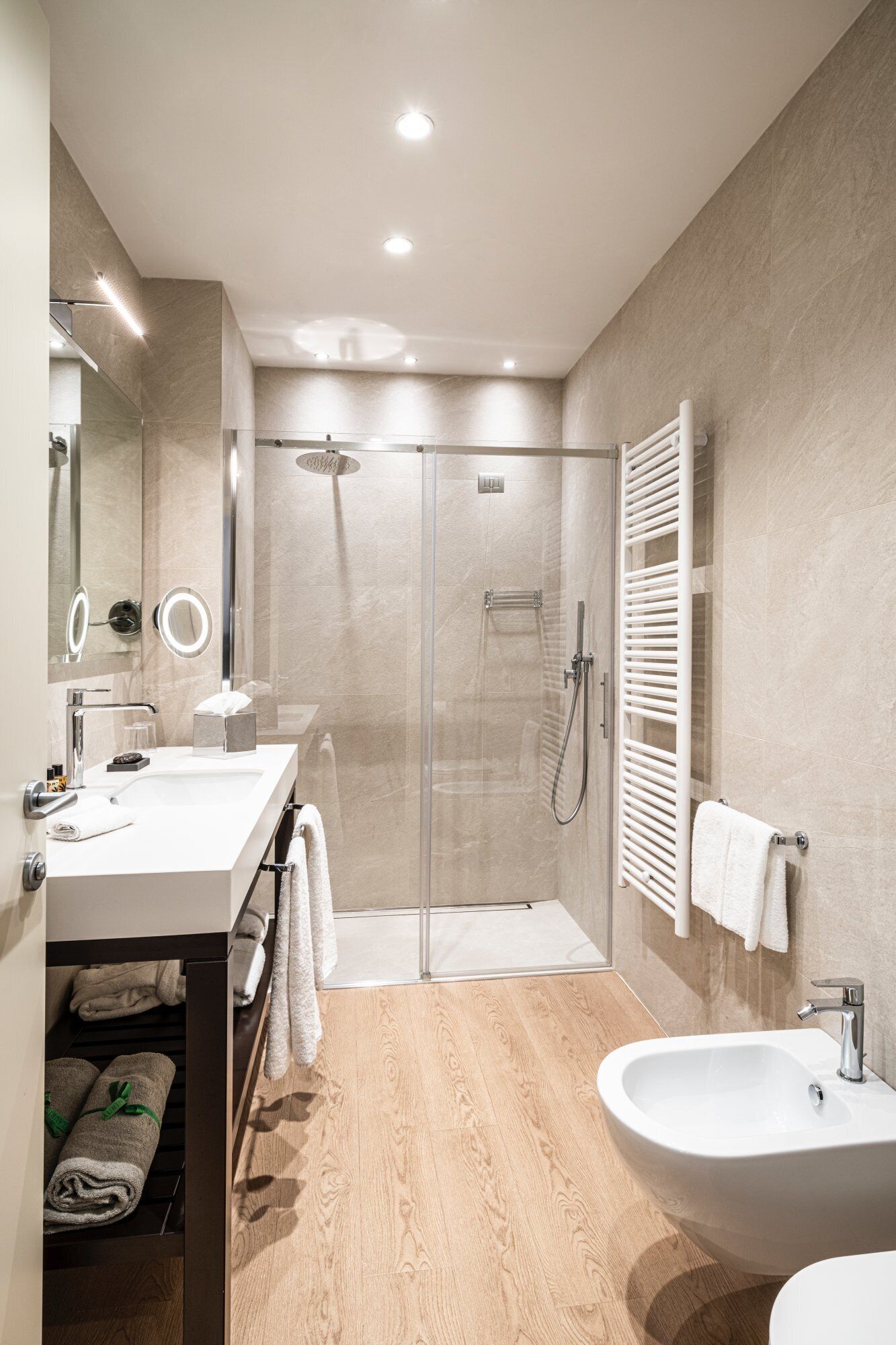 Un baño moderno con ducha envuelta en vidrio, tocador con lavabo y bidé.