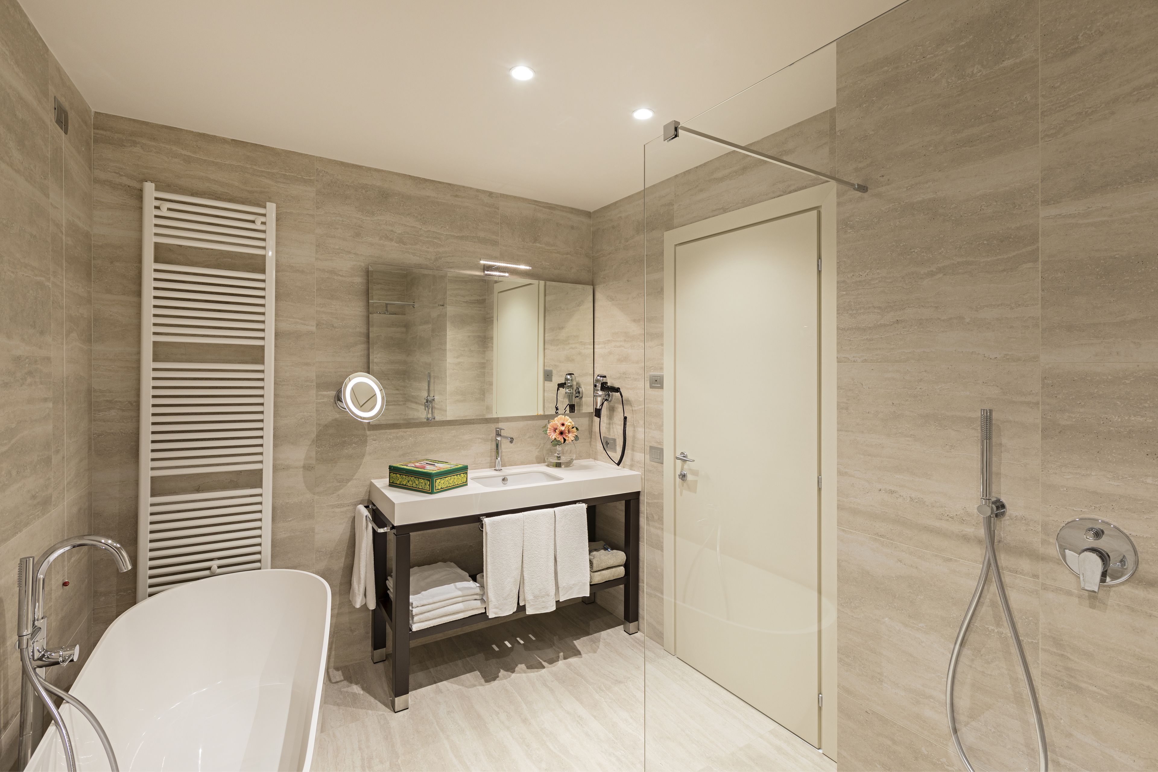 Un bagno moderno con una vasca freestanding, un mobile lavabo con specchio e un box doccia in vetro.