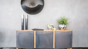 Ein moderner, minimalistischer Konsolentisch mit dunkler Oberfläche, zwei hohe, metallische Vasen, ein kleiner Topfpflanze und einige dekorative Gegenstände.