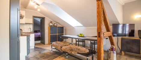 Um espaço de estar moderno estilo loft, com área de refeições, cozinha e uma grande janela que proporciona luz natural.