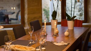 A dining table set with wine glasses, a candle, and a vase with orchids. - Aux Bories de Marquay (Marquay)