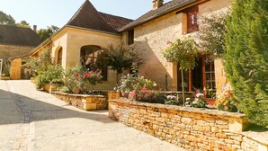 A stone building with a tiled roof, a stone wall, and a gravel driveway. - Aux Bories de Marquay (Marquay)