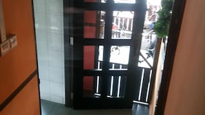 Um corredor com porta dando para área externa, tapete de boas-vindas e parede revestida com azulejos.