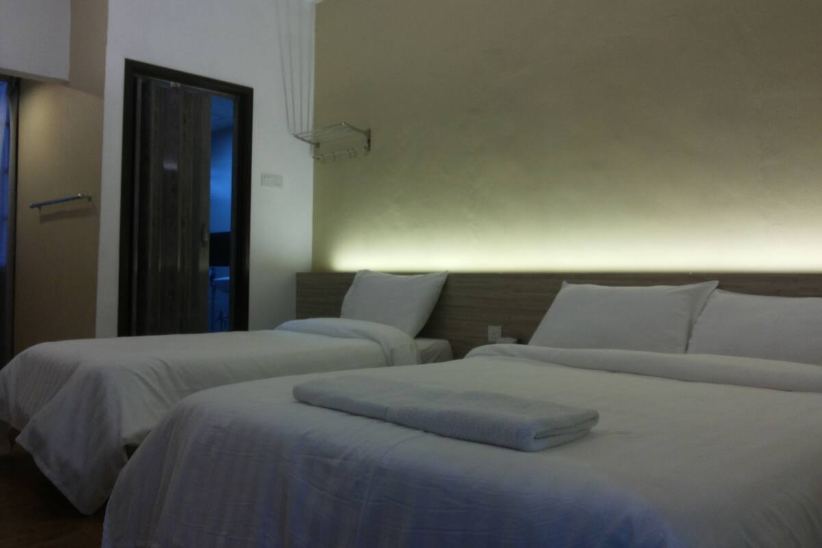 A hotel room with two beds, a wooden headboard, and a door leading to a balcony.